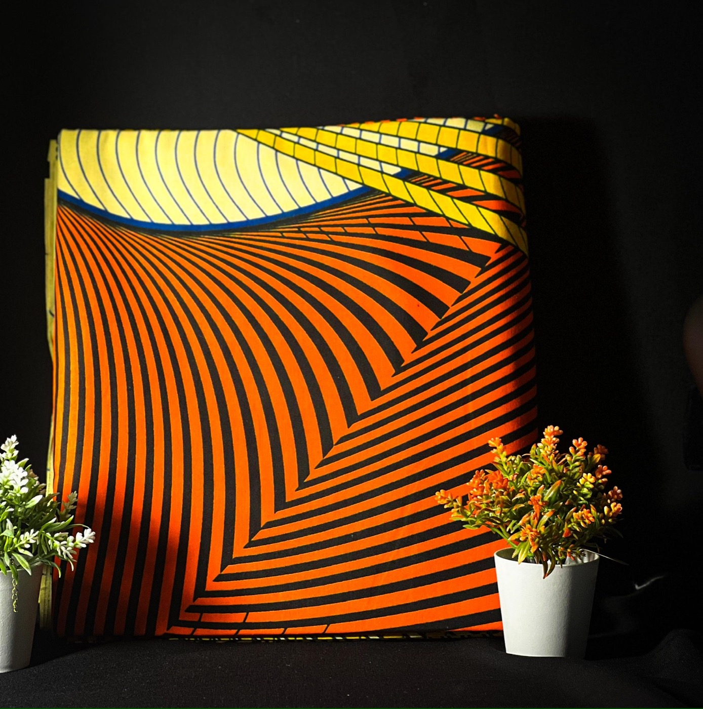 Orange, yellow, and black striped fabric folded on a black backdrop